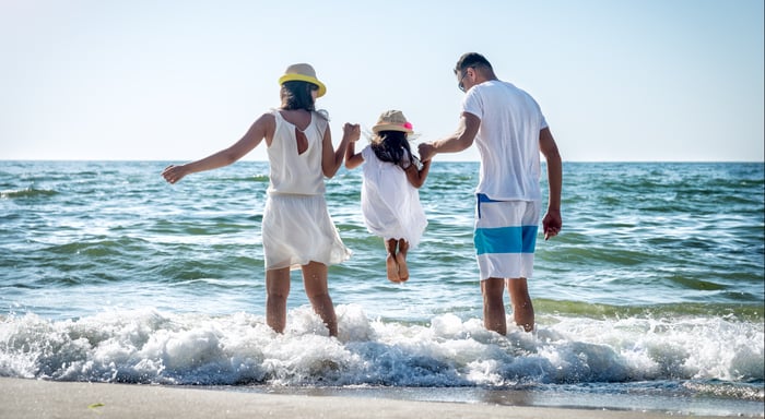 Familie som holder hender på stranden